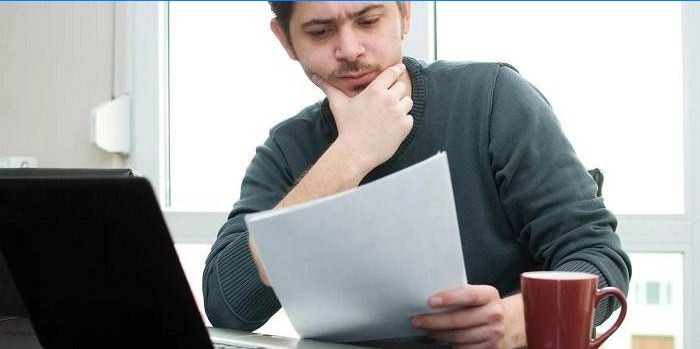 Egy ember egy laptop mellett dokumentumokat tanul