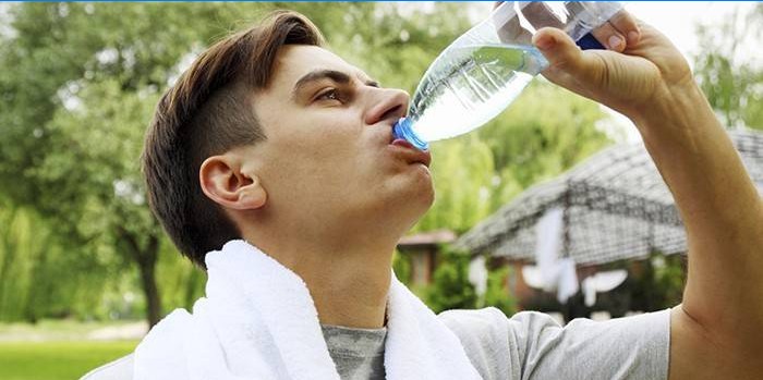 Az ember iszik vizet egy üvegből